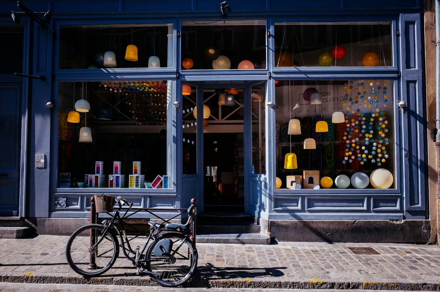 A small lighting store with a variety of lamps and lights on display with a blue bicycle in the foreground